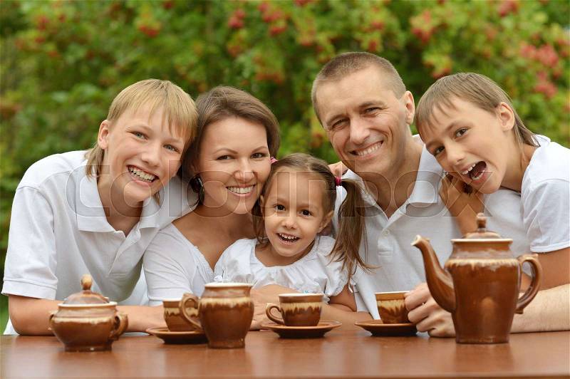 Portrait of a happy family drinking tea together outdoors, stock photo
