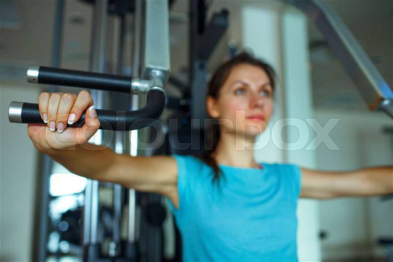 Athletic woman works out on training apparatus in fitness center, stock photo