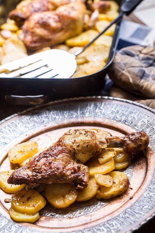 Roasted chicken leg with potatoes with caraway and garlic, stock photo