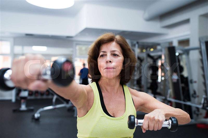 Senior woman in sports clothing in gym working out with weights. Close up of hands, stock photo
