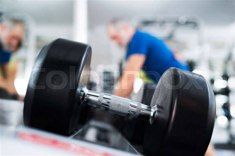 Close up of dumpbell, senior couple in gym working out with weights, stock photo