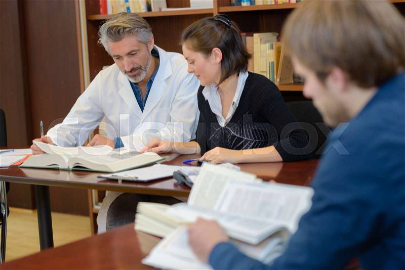 Medical students studying in the library with doctor, stock photo
