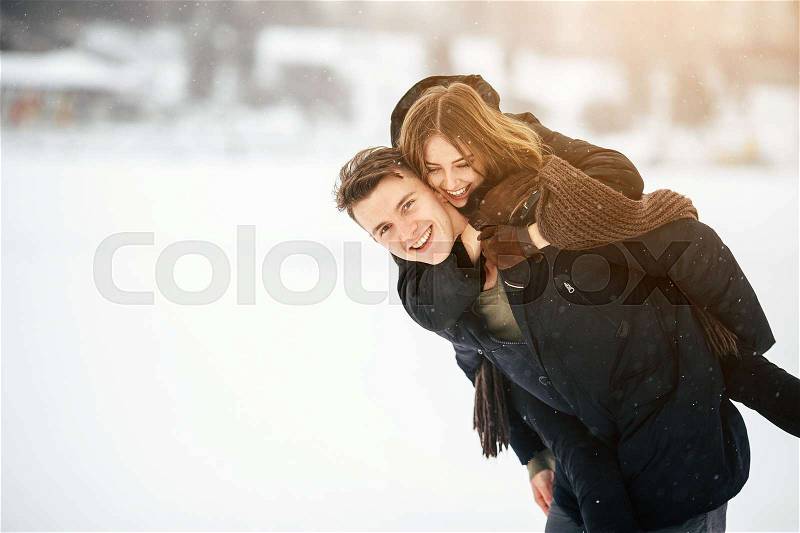 Man carries his girlfriend on the back in the park, in winter holidays, stock photo