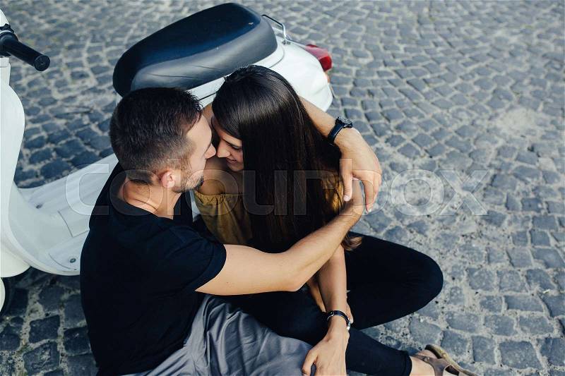 Cute couple with their scooter on a sunny day in the city, stock photo