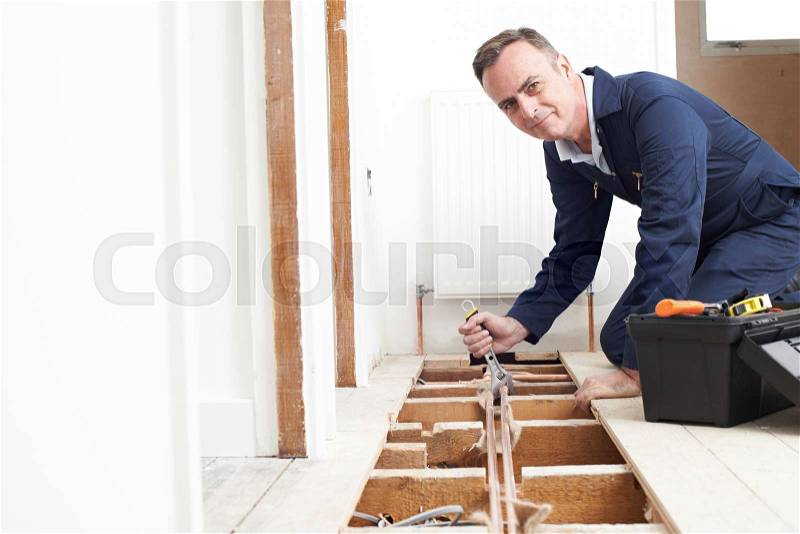 Plumber Fitting Central Heating System In House, stock photo