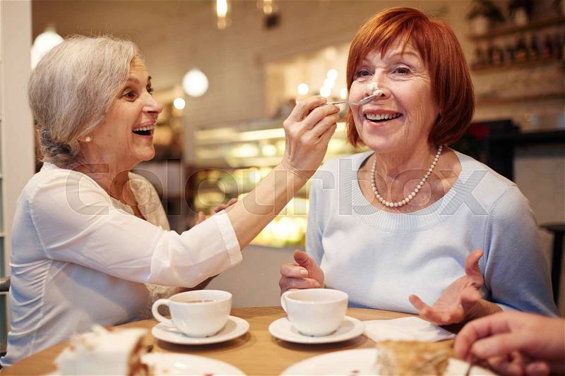 Senior women having fun while enjoying dessert and tea, stock photo
