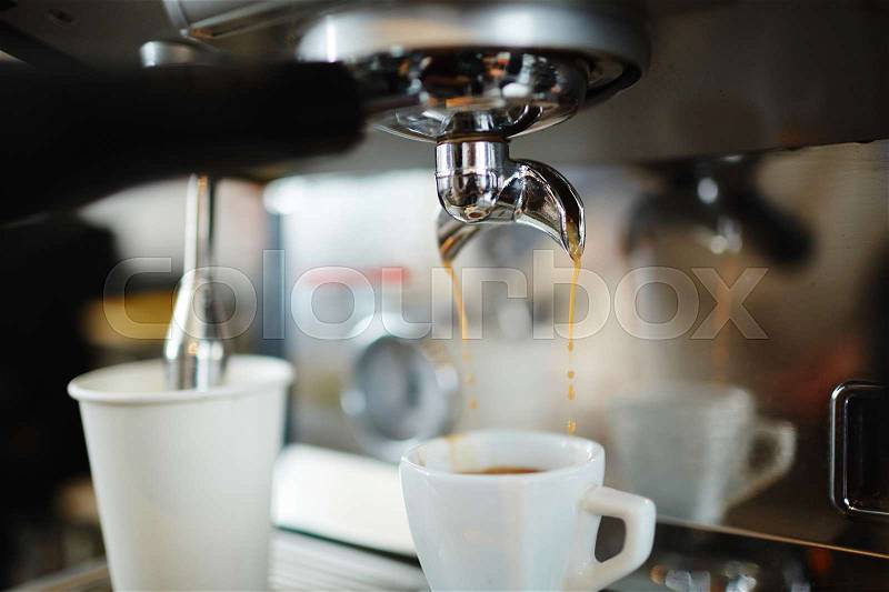 Fresh cappuccino pouring into porcelain cup, stock photo
