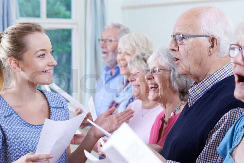 Group Of Seniors With Teacher Singing In Choir Together, stock photo