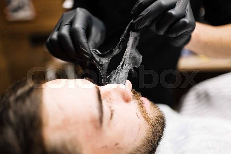 Relaxed man having peel-off mask on face, stock photo