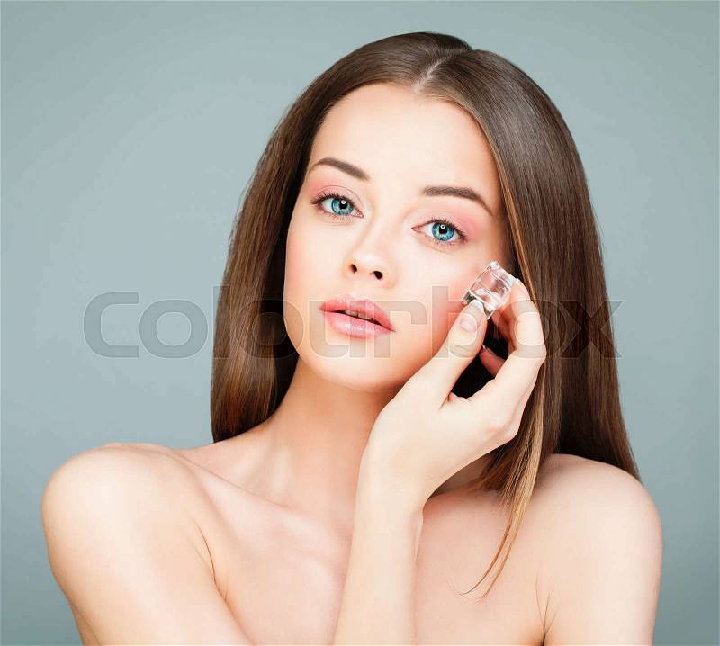 Spa Model Woman with Healthy Skin holding Ice Cubes. Young Perfect Woman on Gray Background, stock photo