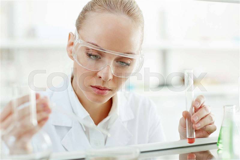 Young clinician or scientist stusying liquid substances, stock photo