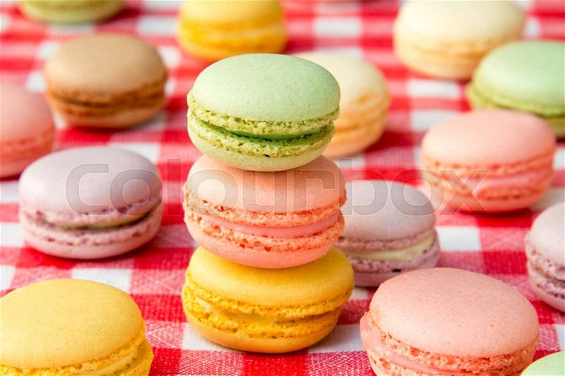 Traditional colorful french macaroons on checkered tablecloth, stock photo