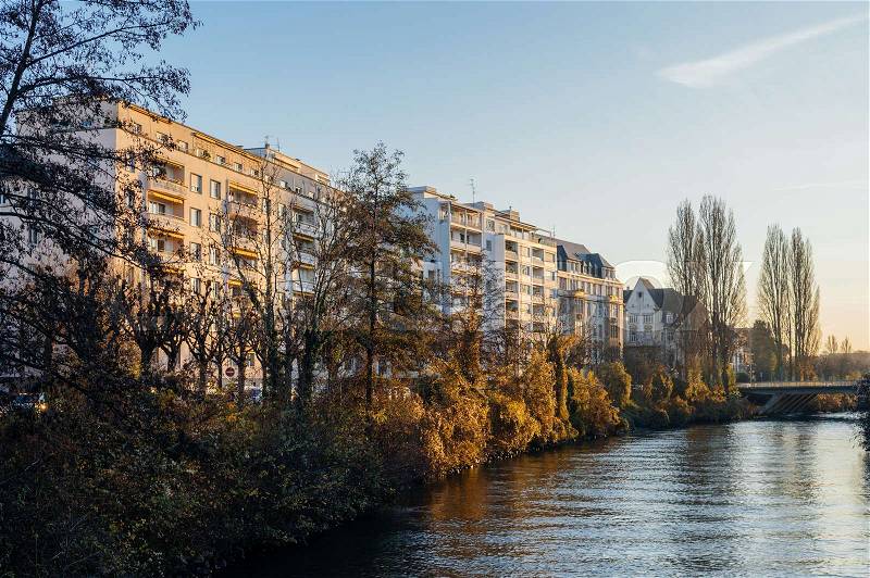 French apartment buildings alongside Ill river bankside on a calm winter day, stock photo