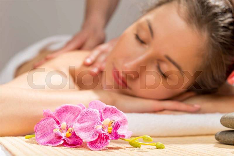 Orchid on a massage table in the spa cabinet and a woman\'s face, stock photo