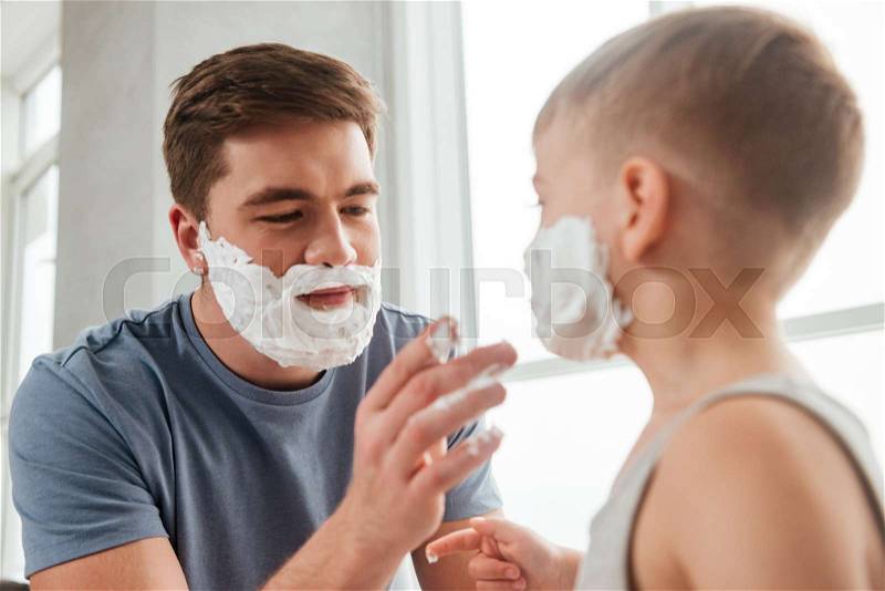 Photo of father and son are applying shaving foam on their faces, stock photo