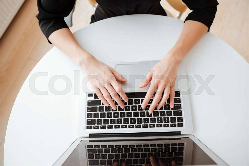 Top view photo of young lady worker sitting in office while using laptop computer and typing by keyboard, stock photo