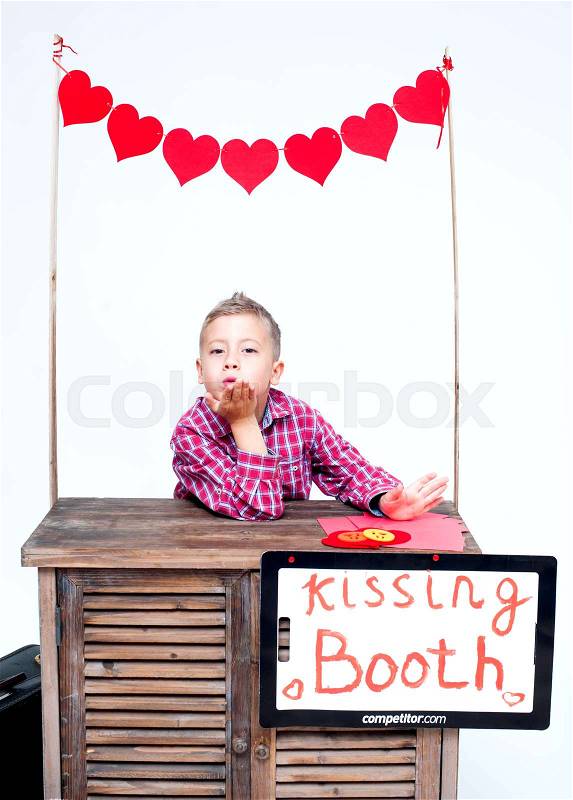 Blond boy in a booth kissing sends kiss, stock photo