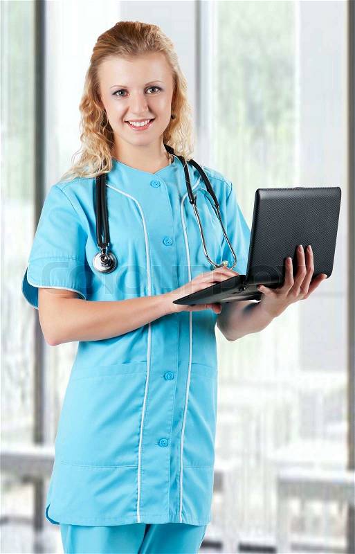 Beautiful young doctor with laptop and stethoscope in hospital, stock photo