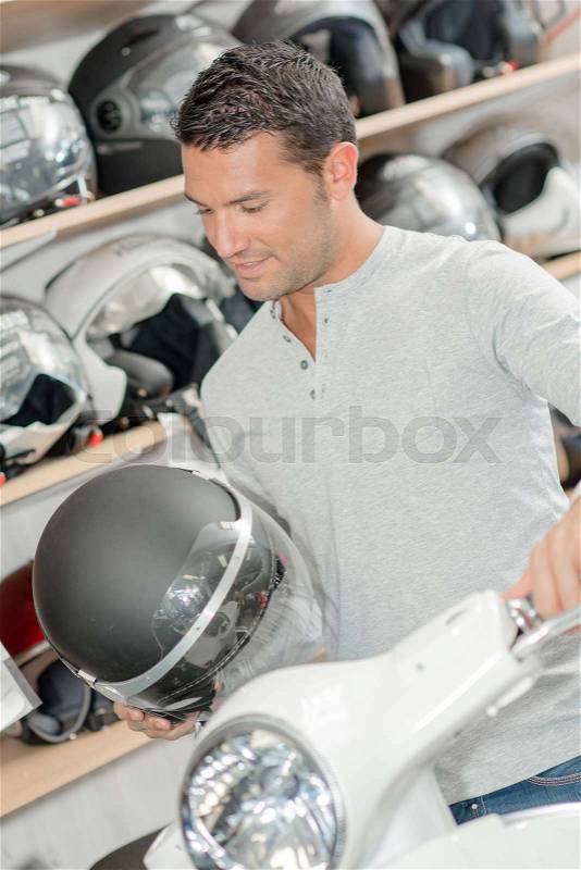 Man holding crash helmet and handlebar of scooter, stock photo