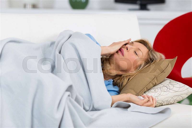 Beautiful ill old woman lying on couch at home, stock photo