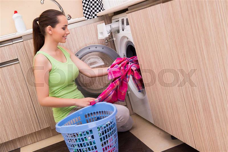 Young wife woman washing clothes near machine, stock photo