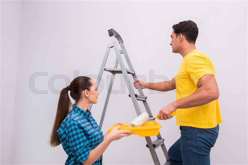 Young couple painting wall at home, stock photo