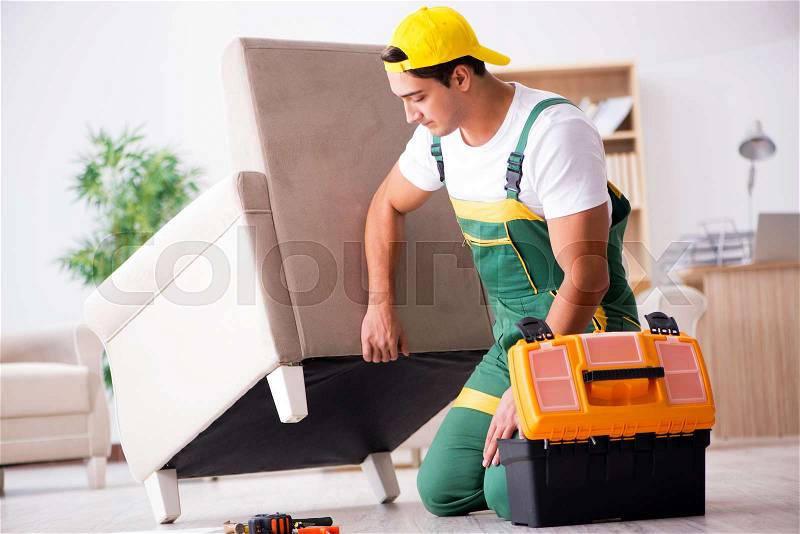 Furniture repairman repairing armchair at home, stock photo