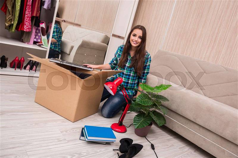 Young woman packing personal belongings, stock photo