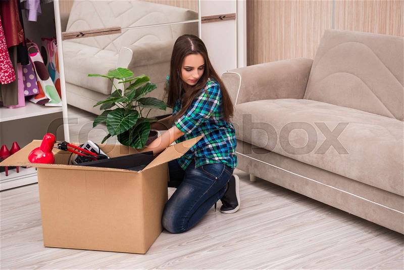 Young woman packing personal belongings, stock photo