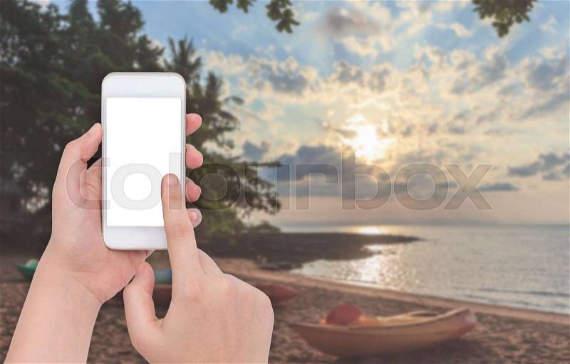 Female hand holding a phone on blur sea with blue sky, stock photo
