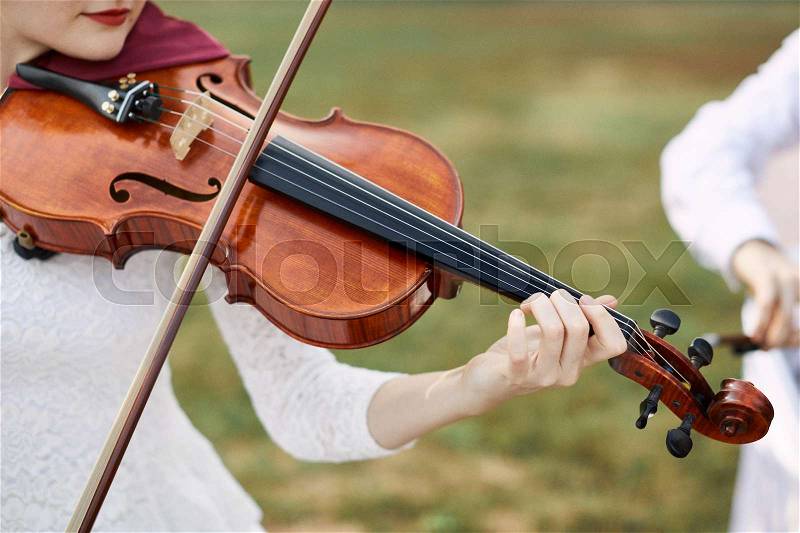 Violinist woman. Young woman playing a violin outside, stock photo