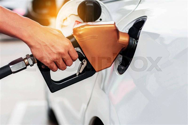 Hands holding a fuel nozzle on cars, stock photo