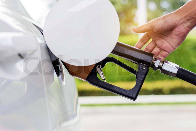Hand with the fuel nozzle inside a car, stock photo