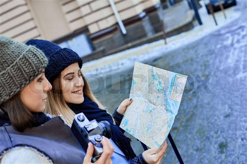 Two friends tourists choose attractions on the paper map, stock photo