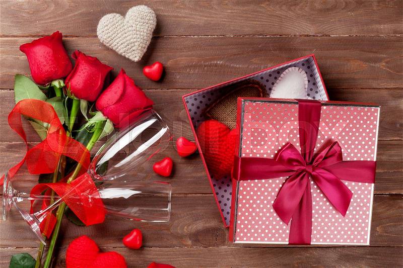 Valentines day gift box with hearts, red roses and champagne glasses on wooden table. Top view, stock photo