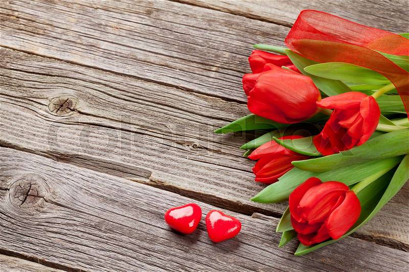 Red tulips and Valentine\'s day candy hearts on wooden table. Top view with copy space, stock photo