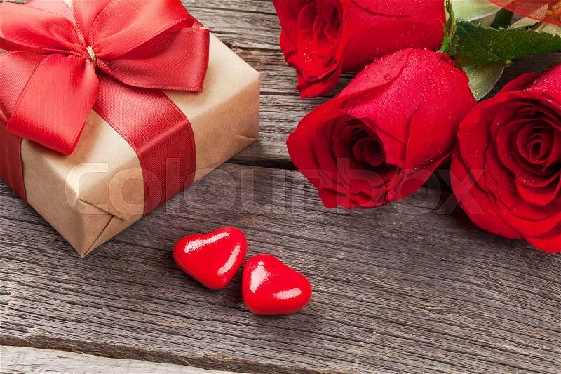 Valentines day gift box, roses and candy hearts over wooden table, stock photo