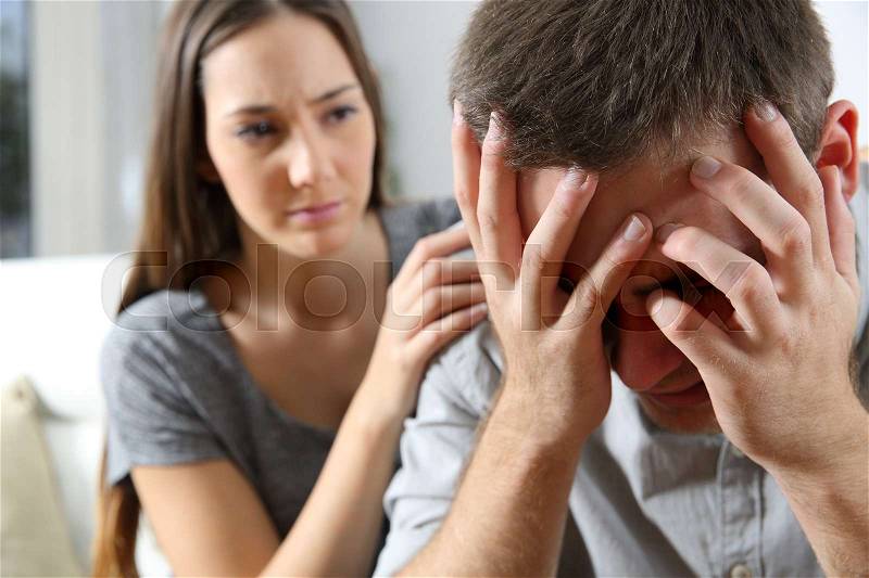 Sad man and a friend or girlfriend trying to console him at home. Friendship concept, stock photo
