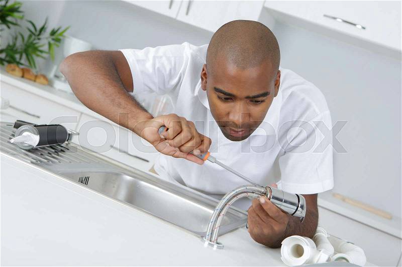 Plumber fixing faucet, stock photo