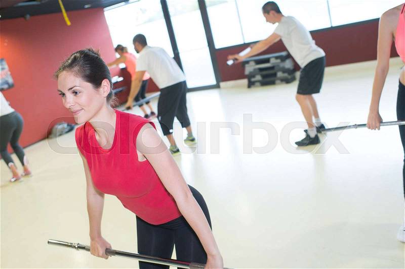 Woman in exercise class using metal bar, stock photo