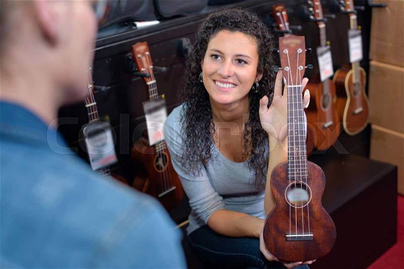 Woman showing miniature guitar, stock photo
