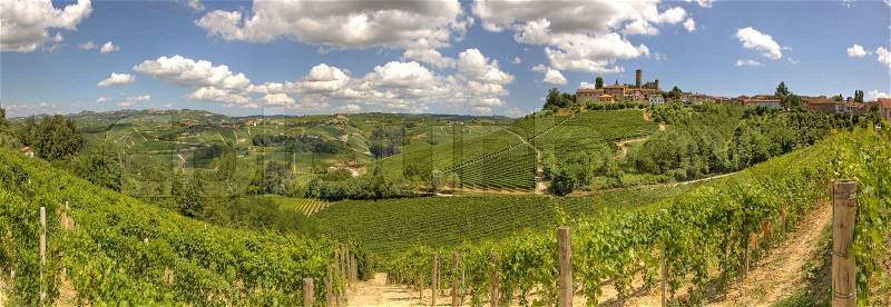 Panoramic view on vineyards and small town on the hill under beautiful sky in Piedmont, northern Italy, stock photo