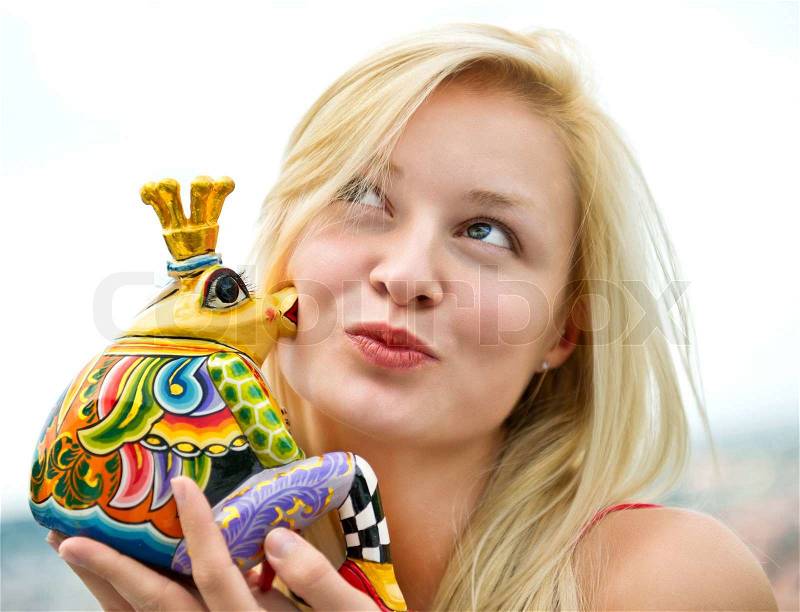 Frog prince being kissed by a beautiful blonde girl, stock photo