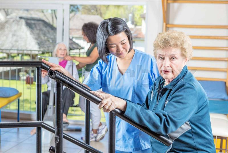 Rehab clinic gym. Multi racial nurses helping elder patients, stock photo
