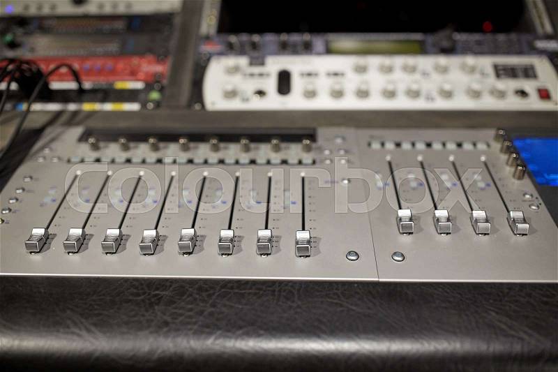 Music, technology, electronics and equipment concept - mixing console at sound recording studio, stock photo