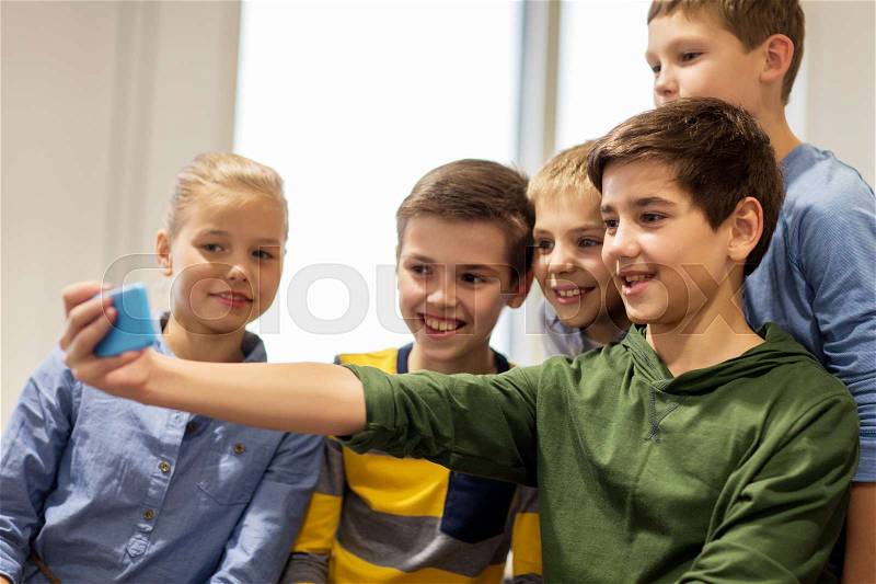 Technology, children and people concept - group of happy kids or friends taking selfie with smartphone, stock photo