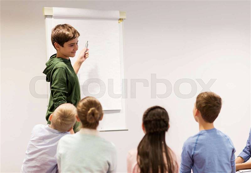 Education, elementary school, learning and people concept - happy student boy with marker writing on flip board, stock photo