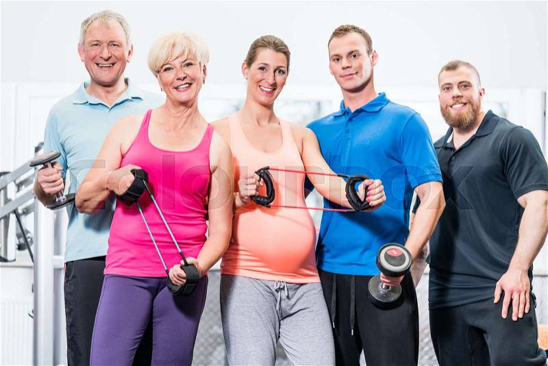 Group of people in gym with stretch bands and dumbbells, stock photo
