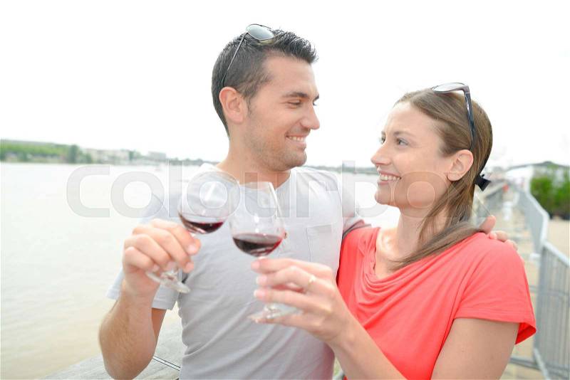 Couple next to river, toasting with red wine, stock photo