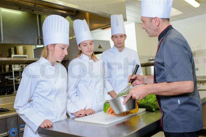 Cooking lesson with three apprentices, stock photo